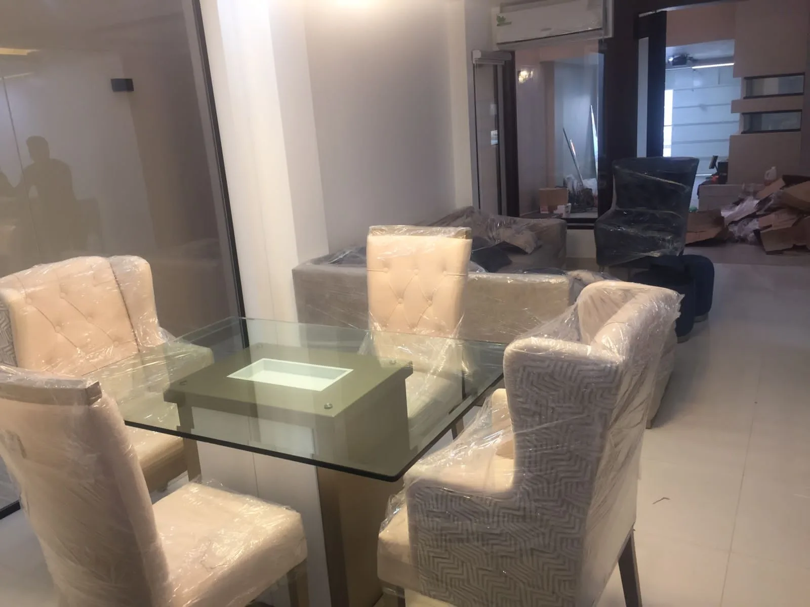 Comedor escena de mudanza/entrega con sillas y sofás envueltos en plástico