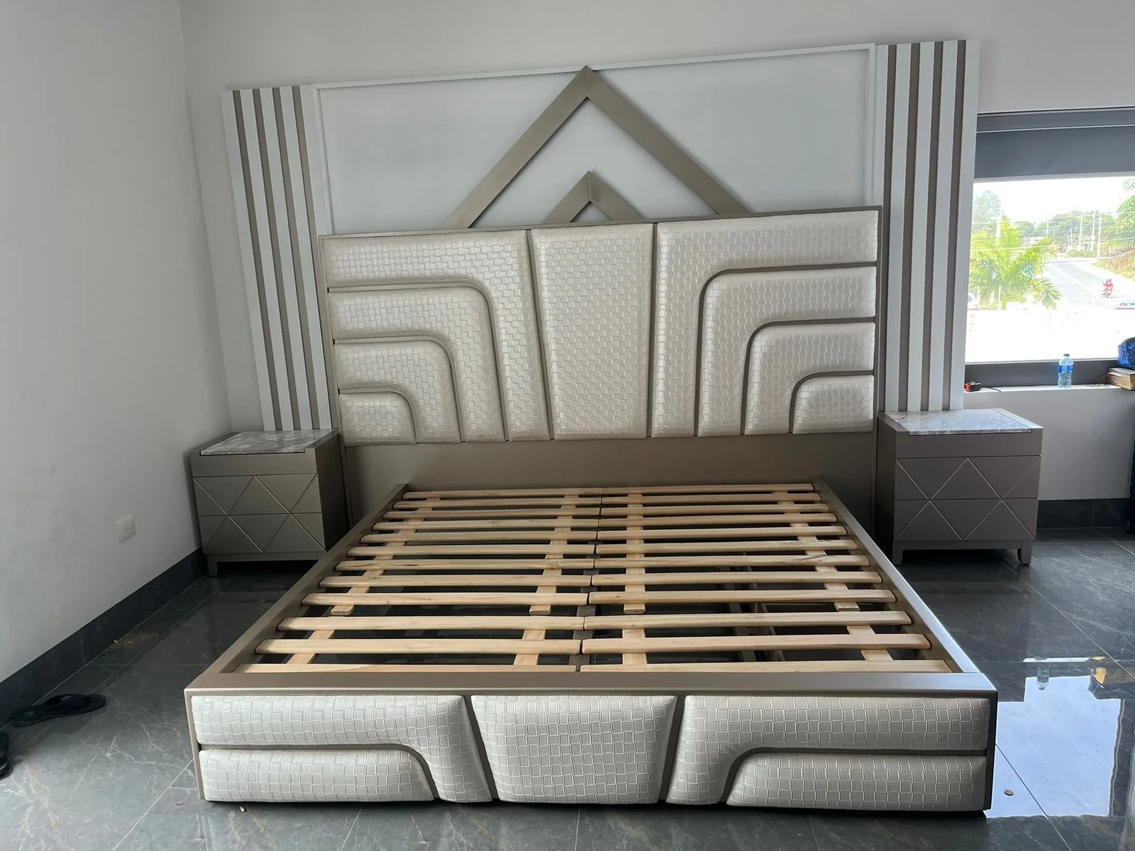 Cabecera de cama con textura tejida en canales curvos y remate metálico triangular (estilo art-decó)